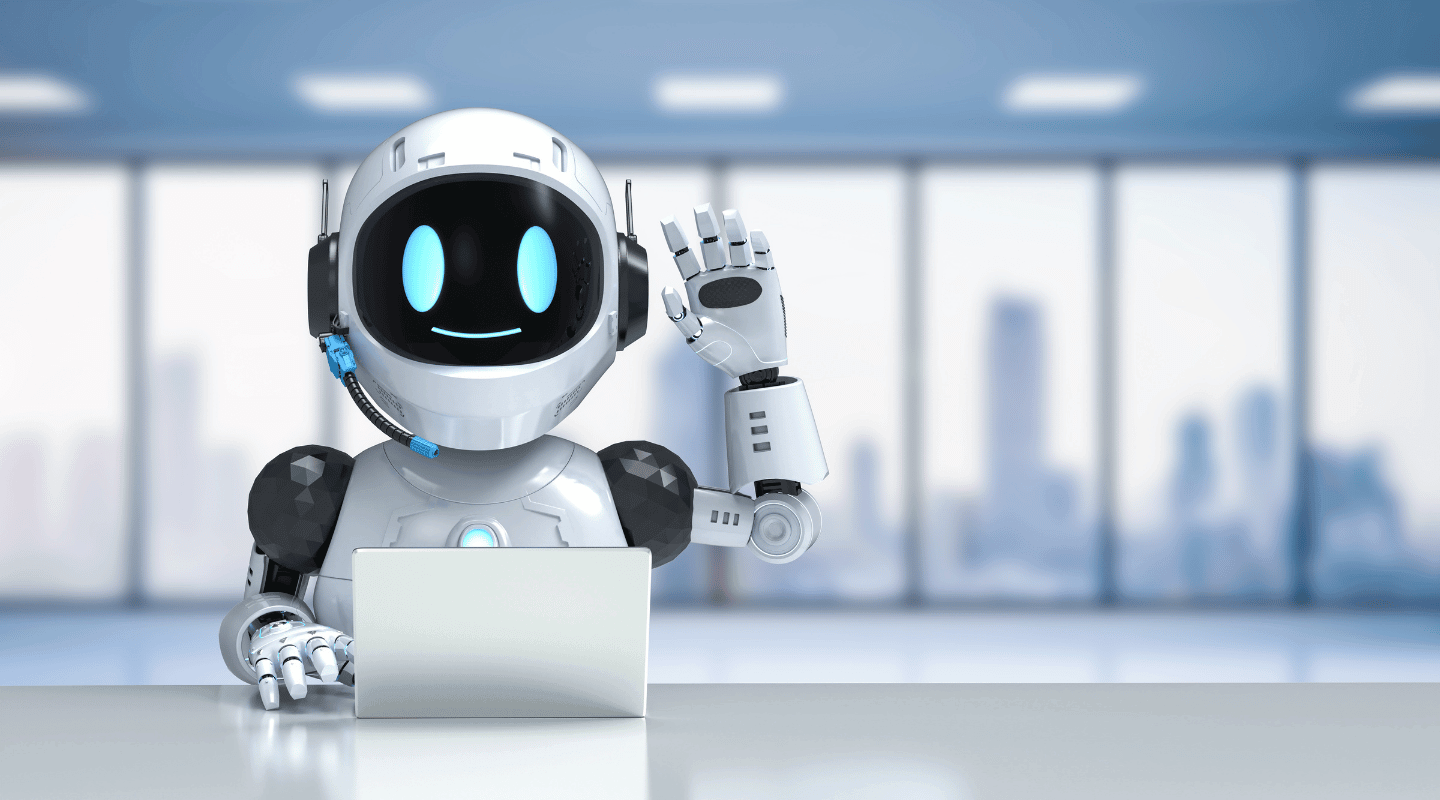 Friendly robot assistant with a headset waving from a desk with a laptop in a modern office.